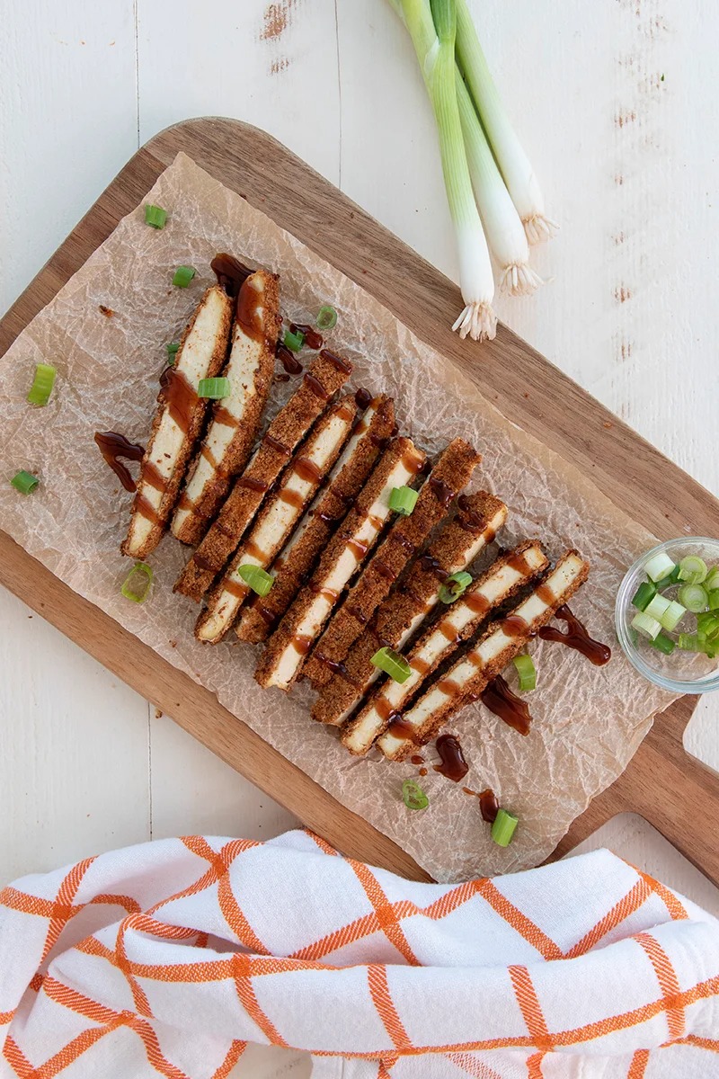 Sliced tofu katsu drizzled with tonkatsu sauce and green onions